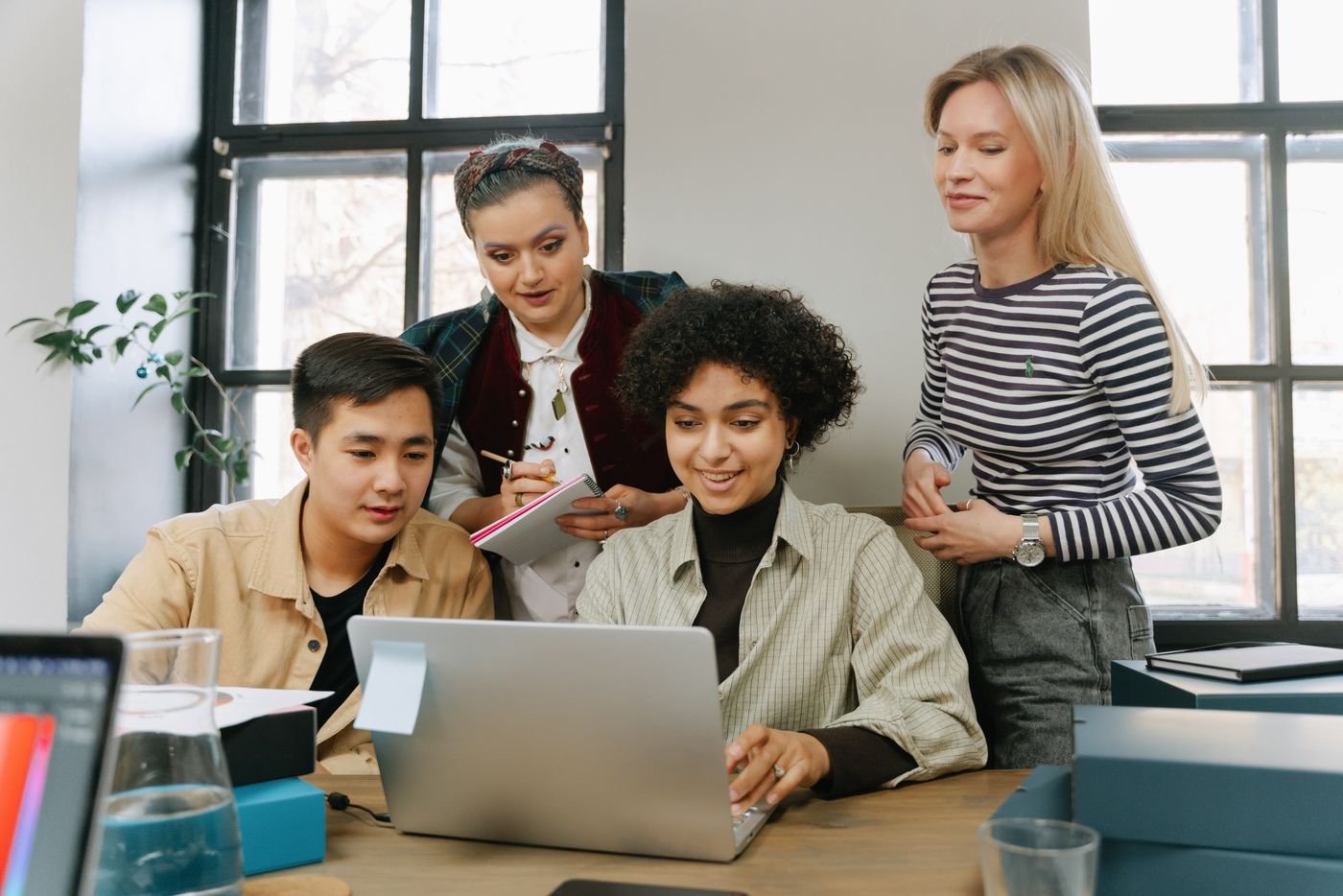 A group of colleagues looking at one laptop together, a picture of shared ownership.