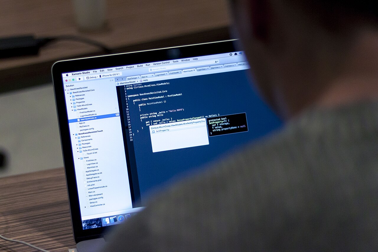 A person working at a laptop with code on screen