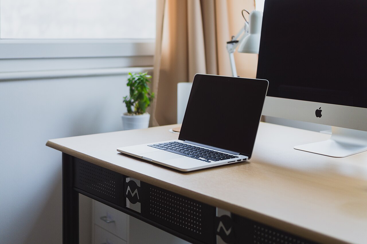 A laptop on a tidy desk with another screen behind it