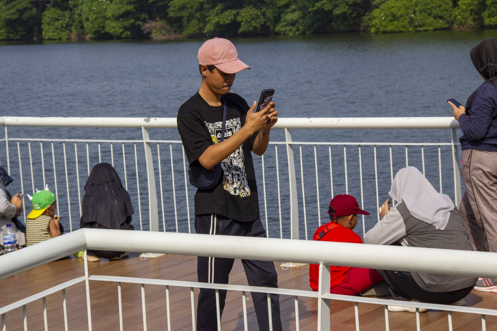 A man looking at a smartphone beside a lake