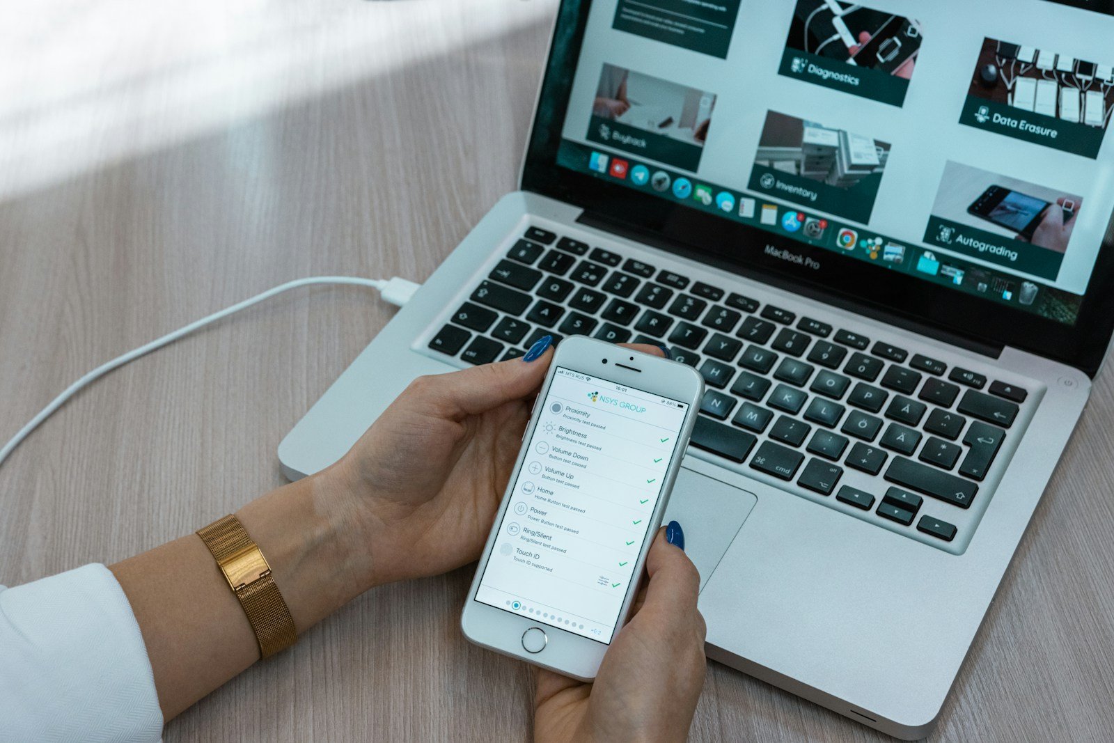 A person using a laptop and mobile phone at a workstation