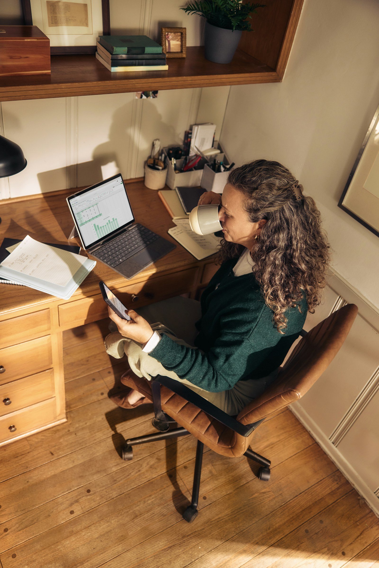 A woman working with a laptop and tablet at a desk